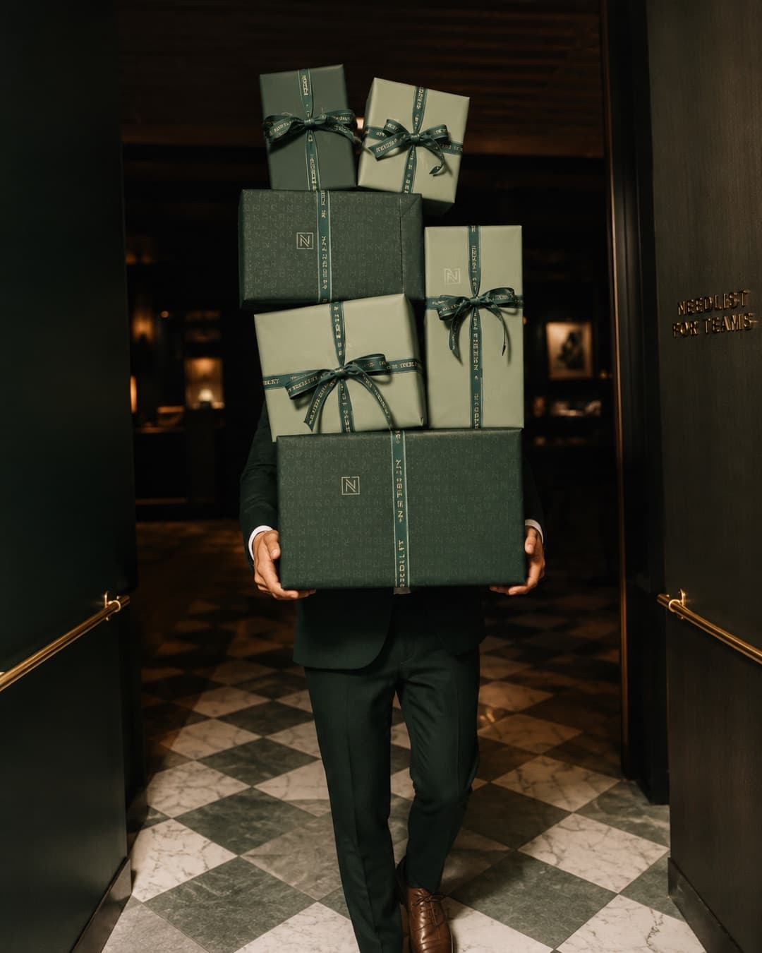 A person carrying a stack of ribbon-tied corporate gifts